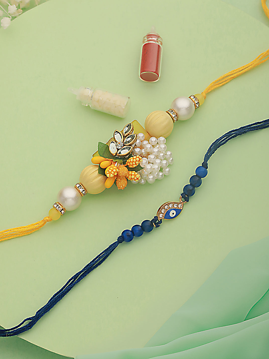 Jazz And Sizzle Unisex Set Of 2 Floral & Evil Eye Rakhi With Roli & Chawal